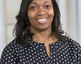 Corporate photo of Candis Polite from the waste up, wearing a navy blue and small white polka-dot top.